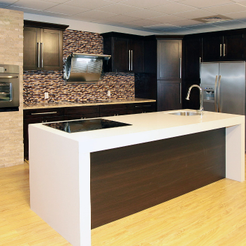 A kitchen with bright wooden floors, marble countertops and dark brown RTA shaker cabinets